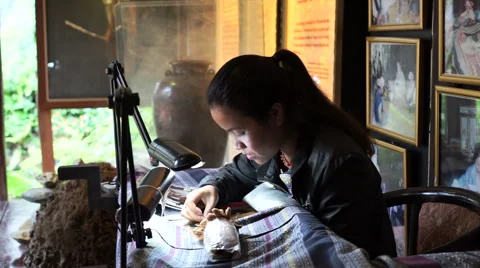 Seamstress is embroiderring patterns on clothes under a lamp in the dark room Stock Footage 67425740