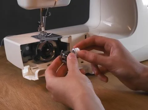 Seamstress hands inserting thread into spool or bobbin of sewing machine, sta 写真素材