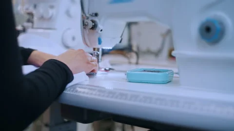 Seamstress hands threading an industrial sewing machine needle Видео 335932080