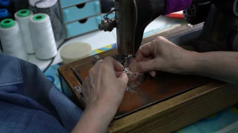 Seamstress inserting thread into needle on sewing machine Stock Footage 223379787