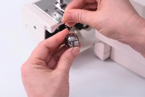 Seamstress inserts bobbin with a thread in sewing-machine. close-up. Foto stock