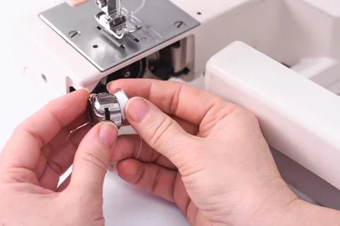The seamstress inserts the spool into the bobbin of the sewing machine. Foto stock