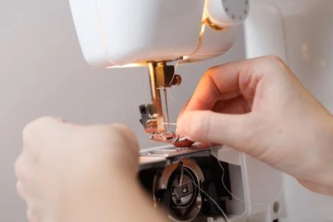 Seamstress inserts thread in sewing-machine 스톡 사진