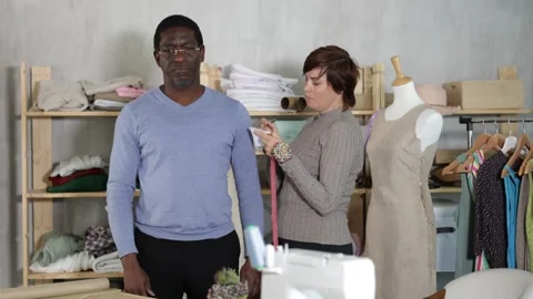 Seamstress measuring client in sewing studio for custom garment Stock Footage 328143216
