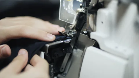 Seamstress operating industrial overlock machine while stitching fabric Video stock 320257814