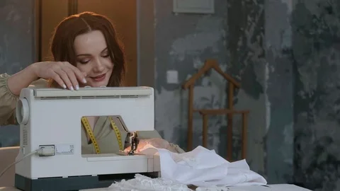 A seamstress prepares a sewing machine to work. In the background mannequin Stock Footage 127477616