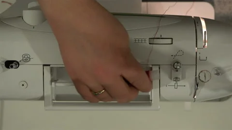 Seamstress puts spool of red thread on a sewing machine and thread stretches Stock Footage 67844752
