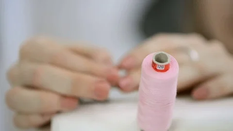 The seamstress rewinds the thread on the bobbin on the sewing machine Stock Footage 74155099