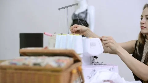 Seamstress sits and white thread inserts into the overlock Stock Footage 73288681