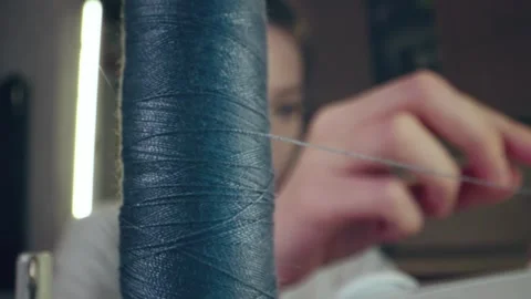 The seamstress slips a thread into the needle eye of a sewing machine, fingers Stock Footage 269810121