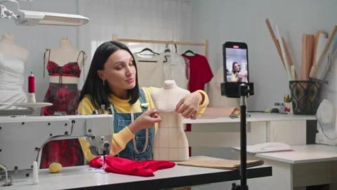 Seamstress takes a video tutorial on her phone, in which she explains in detail 動画素材 276839250
