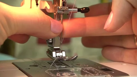 A seamstress is threading the eye of a needle with a needle threader. 스톡 동영상 139062904