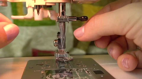 A seamstress is threading the eye of a needle with a needle threader. Stock-Footage 139114606