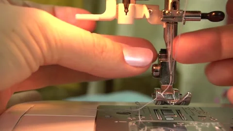 A seamstress is threading the eye of a needle with a needle threader. Stock Footage 140222926