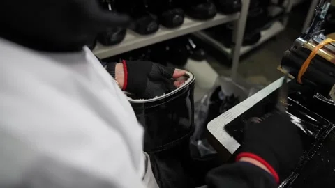 Seamstress trimming thread with scissors after stitching a rubber boot at an Stock-Footage 342897912
