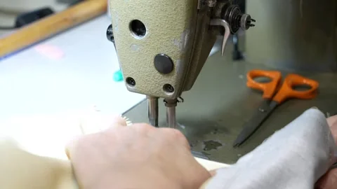 Seamstress using industrial sewing machine for tailoring clothes in a workshop Stock Footage 339404789