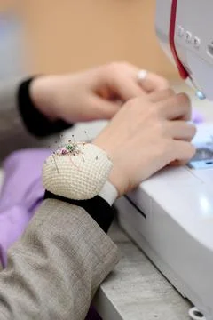 Seamstress using sewing machine with pin cushion on wrist for convenience Stock Photos