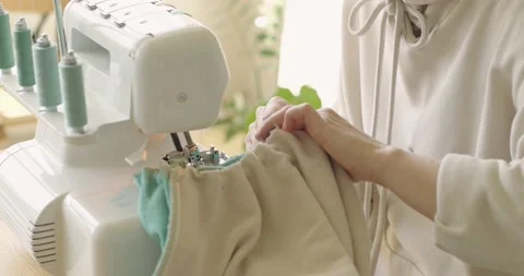 Seamstress using sewing machine while working at home. Designer sews fabric Stock Footage 201196220