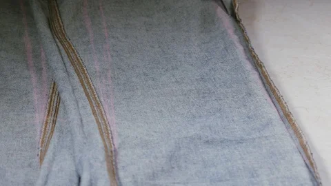 Seamstress when working with scissors cuts a piece of blue fabric on the table Stock Footage 105660638