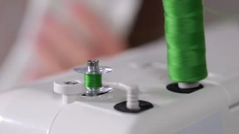 Seamstress winding green thread on bobbin Stock Footage 303876810