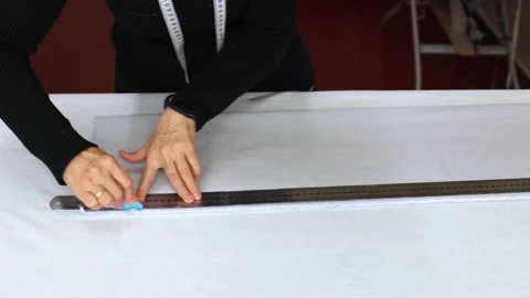 Seamstress at work with ruler measures piece of tissue on table in workshop Stock Footage 167969270