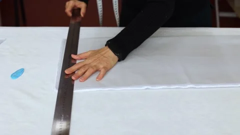Seamstress at work with ruler measures piece of tissue on table in workshop Stock Footage 168376334