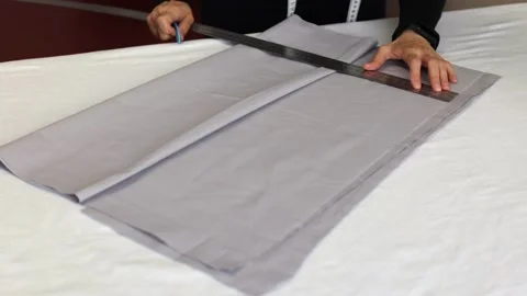 Seamstress at work with ruler measures piece of tissue on table in workshop Stock Footage 169690968