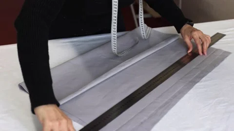 Seamstress at work with ruler measures piece of tissue on table in workshop Stock Footage 187700853