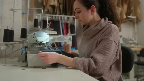 Seamstress work on the sewing machine. Tailor sits at the table and scribbling o Stock Footage 151386066
