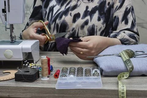 Seamstress At Work Using Scissors And Sewing Machine With Fabric And Tools Stock Photos