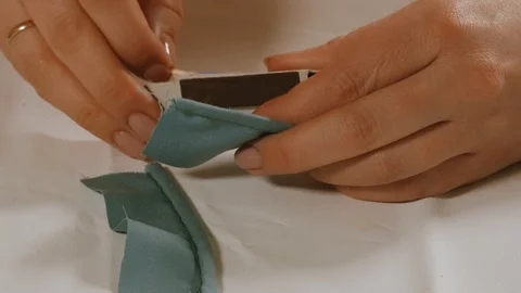 Seamstress working with matches, searing thread on a piece of blue fabric for Stock Footage 105659274