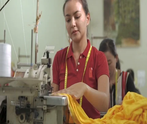 Seamstress is working on a sewing machine at a clothing factory Stock Footage