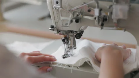 Seamstress in the workplace. close-up view of hands sewing some clothes with Stock Footage 228917479