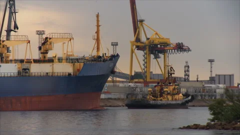 In the seaport, a powerful tug pulls a huge merchant ship in the narrow strait Stock Footage 92234495