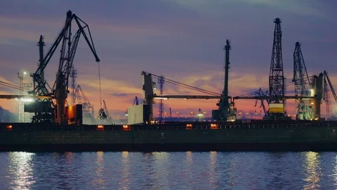 In the seaport of a sunset. Large cranes load bulk cargo in a cargo vessel Stock Footage 91630600