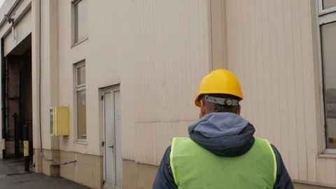A seaport worker with a beard and a helmet is walking. back view Stock Footage 99352145