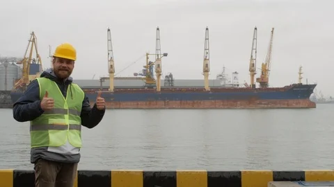Seaport worker with a beard and a helmet makes like Stock Footage 99352182
