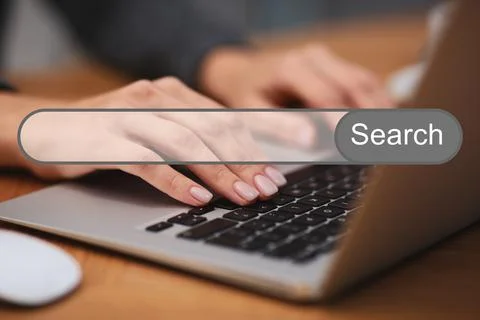 Search bar of internet browser and woman working with laptop at table indoors Stock Photos