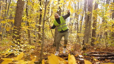 Search for a missing person in the autumn forest. A bearded man in a bright Stock Footage 220782922