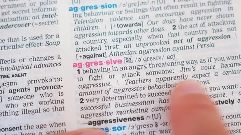 Searching for and finding a word aggressive definition in a dictionary Stock Footage 97923886