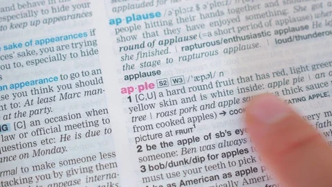 Searching for and finding a word apple definition in a dictionary Stock Footage 97923593