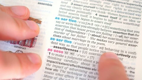 Searching for and finding a word assertive definition in a dictionary Stock Footage 97925197