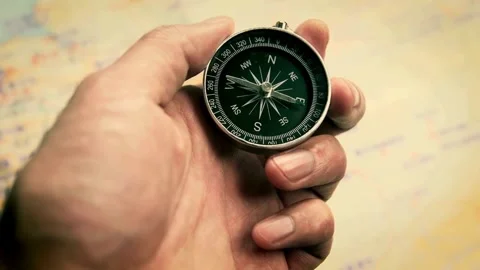 Searching direction with compass. Mans hand holding a compass over a map, c.. Stock Footage 257871791