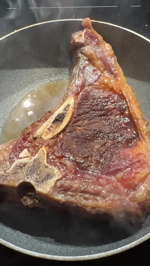 Seared beef steak sizzling in frying pan browned crust, smoke, close-up cooking Stock Footage 320170824