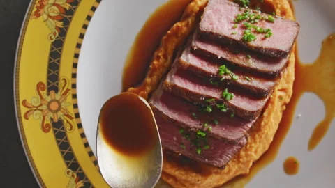 Seared NY strip steak slices on sweet potato purée, drizzled with sauce and garn Stock Footage 332016388