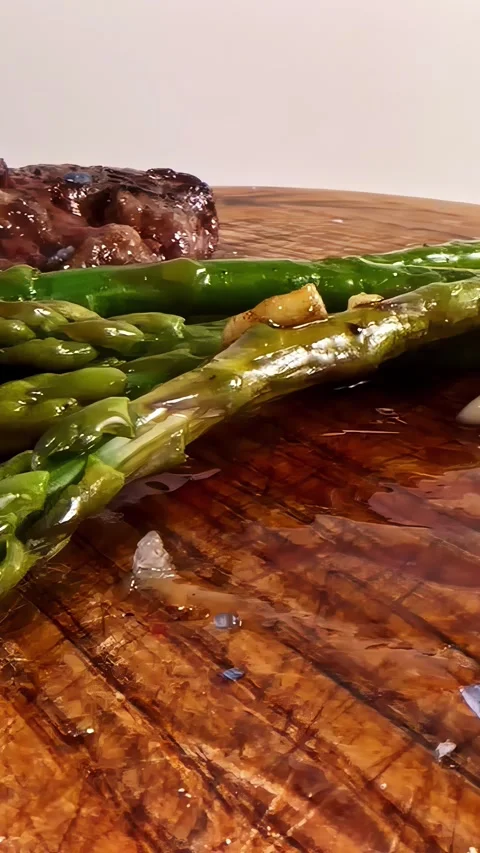 Seared Steak With Asparagus and Roasted Garlic on Wooden Board, Dolly Right 스톡 동영상 338173776