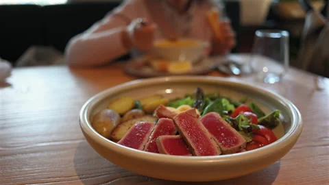 Seared tuna steak slices served with potatoes, fresh salad, tomatoes, and egg on Stock Footage 332623333