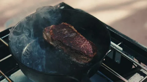 Searing a large steak outside on camp stove Stock Footage 277009288