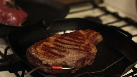 Searing a thick ribeye steak on a cast iron grill pan for perfect char marks Stockbeeldmateriaal 340563217