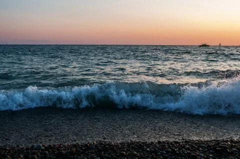 Seascape and sunset, turquoise waves and orange sky Stock Photos